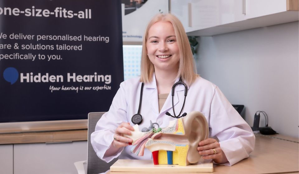 Doctor Clodagh Gallagher smiling while holding a physical anatomical ear scultpture