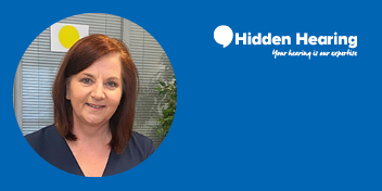 A professional portrait features a blurred-faced individual with straight, shoulder-length auburn hair, set against an office backdrop with blinds and greenery. The blue frame includes the Hidden Hearing logo with text: 'Your hearing is our expertise.'