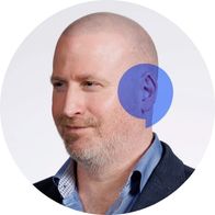 Hidden Hearing audiologist Barry Douglas smiling with a blue speech bubble overlayed on his ear