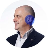 Audiologist Enda Dooley smiling with a blue Hidden Hearing branded speech bubble overlayed on his ear
