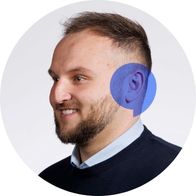 A photograph of Hidden Hearing audiologist Stephen Redmond smiling with a blue speech bubble overlayed on his ear