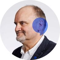 A photograph of hearing aid audiologist Ivor Lewis smiling in a suit