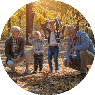 [GEN] A smiling older couple kneels beside two joyful children playing in fallen autumn leaves, surrounded by a sunlit park with golden foliage, highlighting the joy of hearing life's precious moments.