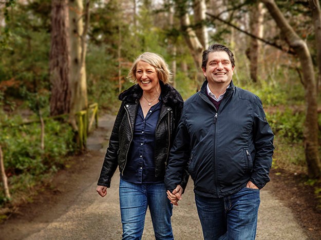 Couple holding hands while walking in a forest trail