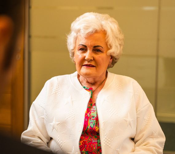 Woman in a colourful top talking to an audiologist in a Hidden Hearing consultation room