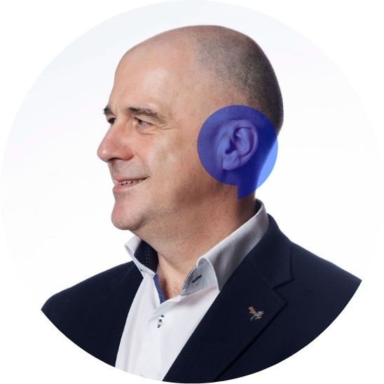 Lead Hidden Hearing audiologist Enda Dooley smiling with a blue speech bubble overlayed on his ear