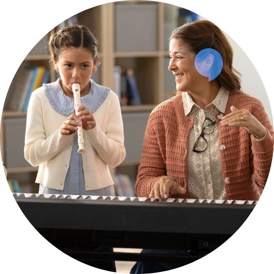Teacher instructing a child playing the recorder while sitting at a piano.
