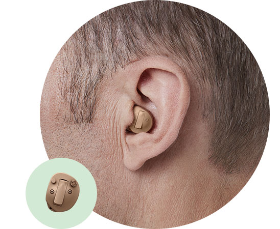 [GEN] A discreet in-the-ear hearing aid sits snugly in a man's ear, designed for comfort and functionality. The inset highlights the device's detailed features. No visible text or branding is present.