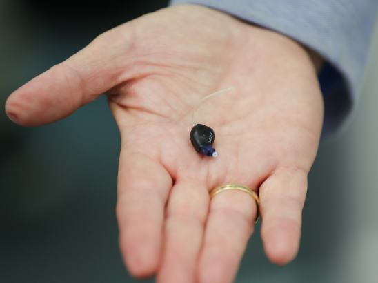 Oticon Zeal hearing aid in a persons hand 