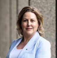 A photograph of Hidden Hearing sales director Tara Finnegan in a light blue suit