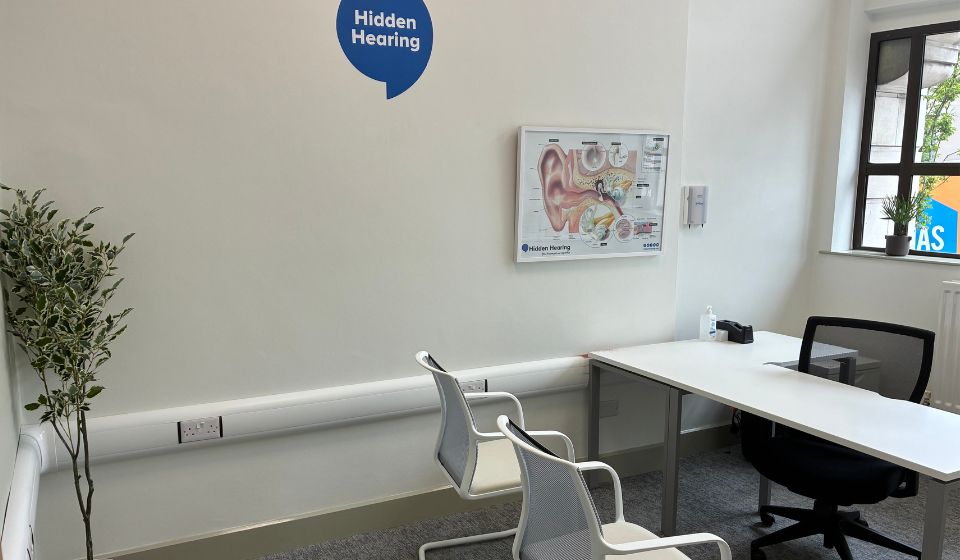 Picture of the consultation room in the Hidden Hearing Omagh location with branding on the wall and an image of an anatomical ear