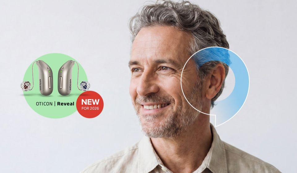 A picture of a man smiling with a blue speech bubble overlayed on his ear indicating he is wearing the brand new state-of-the-art Oticon Reveal