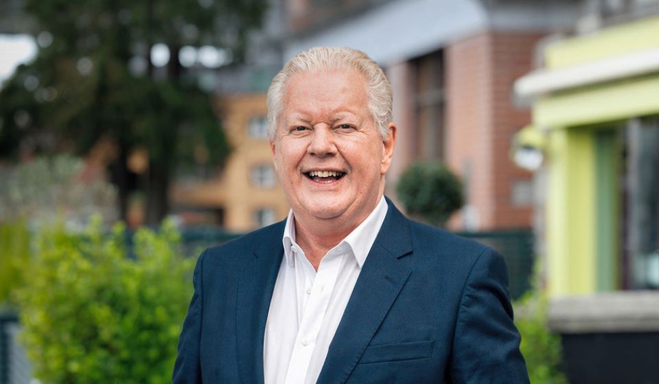 Media personality Julian Simmons smiling in a suit in an urban setting