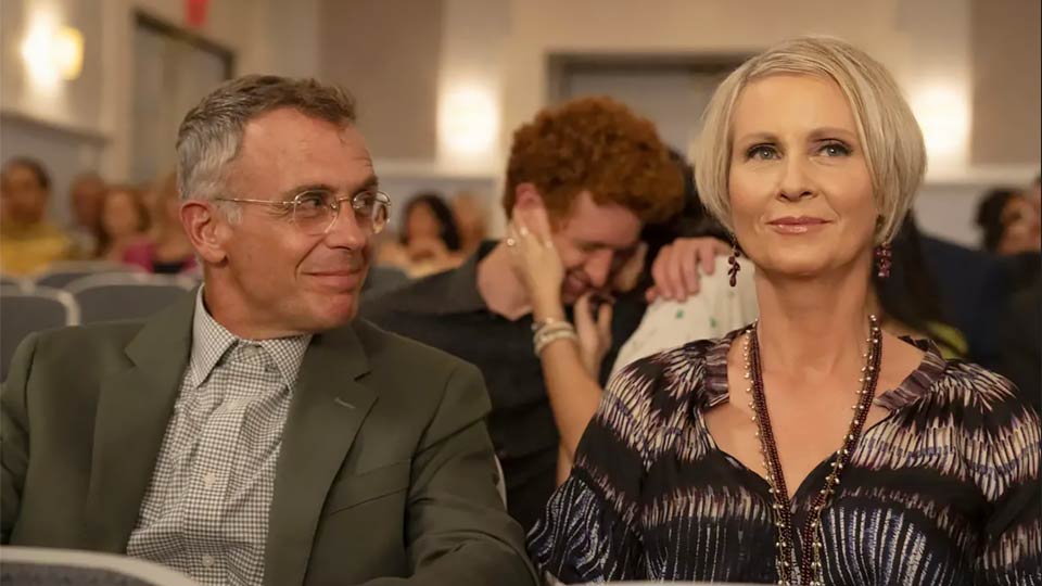 Older couple enjoying a theater performance while seated among other audience members.