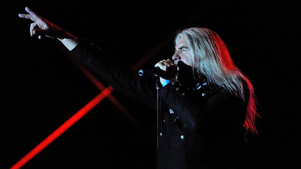 Biff Byford of Saxon performing live under red and black stage lighting.