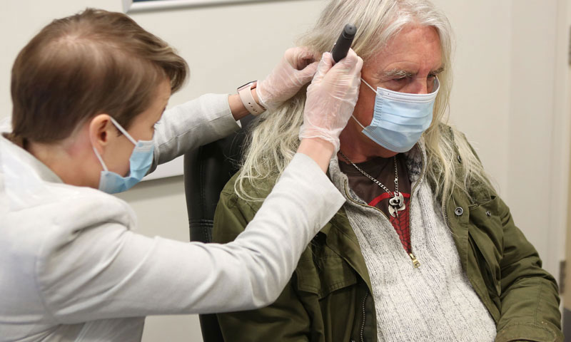 Biff Byford receiving a hearing examination at a clinic.