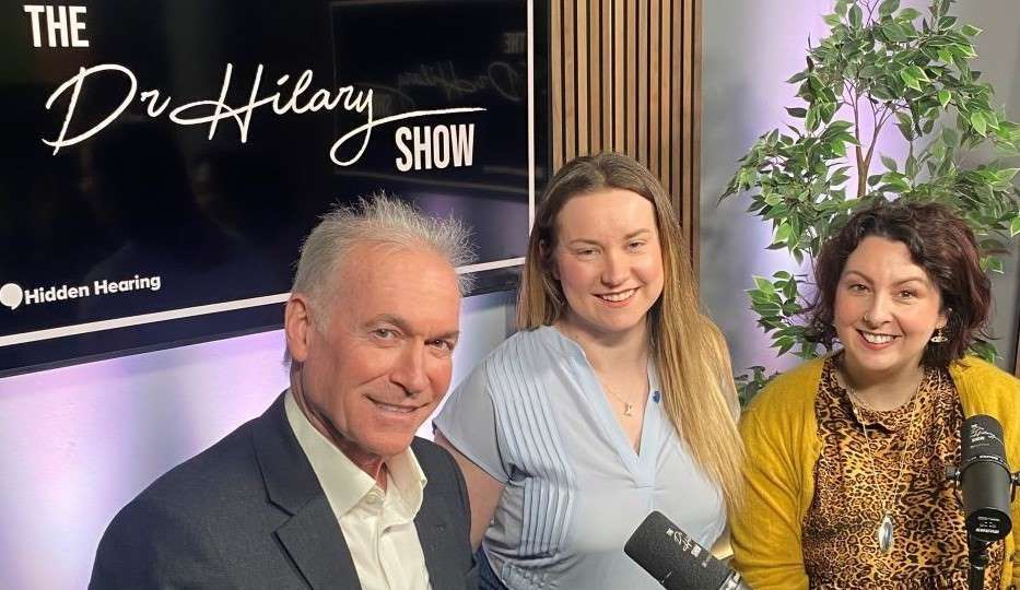 Dr Hilary hosting The Dr Hilary Show with Hidden Hearing branding visible.