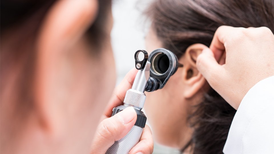 Hearing specialist examining a patient’s ear with a medical instrument.