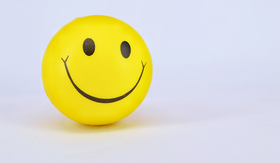 Yellow smiley face stress ball against a white background.