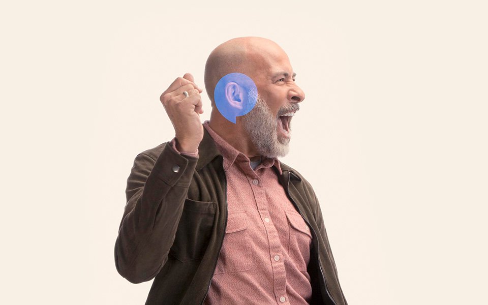 Man with a blue highlighted ear raising his hand, symbolizing awareness for hearing health.