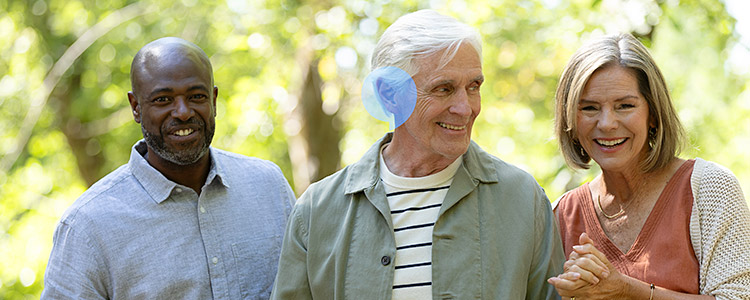 Three people standing outdoors with the man in the center highlighted by a blue bubble over his right ear.