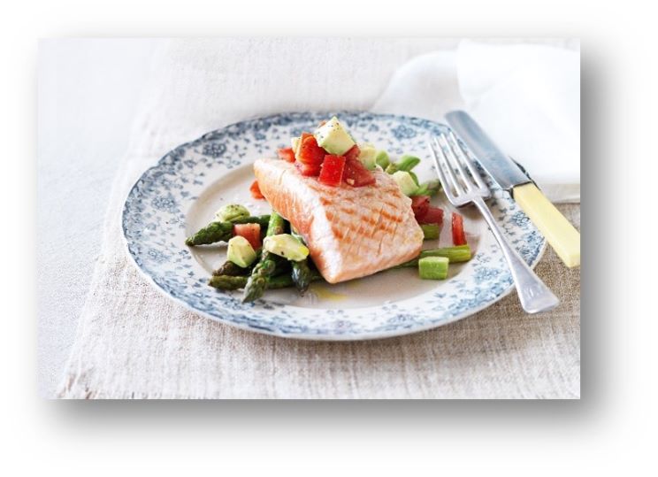 Grilled salmon served on a plate with asparagus, diced avocado, and tomato, promoting healthy eating for better hearing.