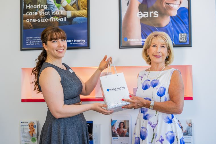 Jennie Bond receives a Hidden Hearing gift bag after a hearing care consultation.