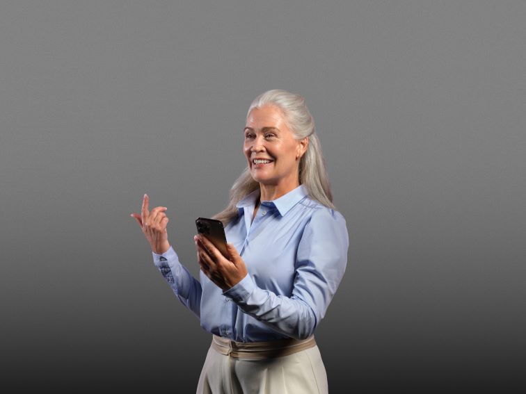 Woman with long gray hair using a smartphone with Oticon Intent hearing aids