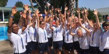 England deaf football team celebrating victory outdoors with medals and a trophy.