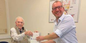 hearing care professional handing over a gift box to an elderly person as part of a give back program