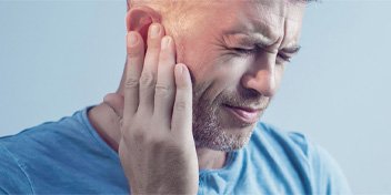 Person touching their ear, possibly experiencing tinnitus symptoms