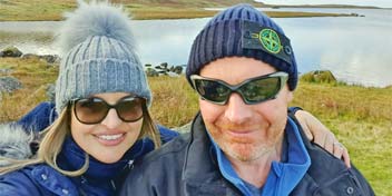 Couple enjoying the outdoors by a scenic lake wearing warm winter hats