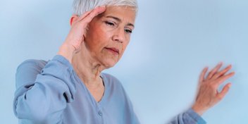 Older adult in a blue shirt appearing unsteady, emphasizing the connection between hearing aids and fall prevention.