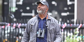 Man outdoors wearing a jacket and binoculars around his neck