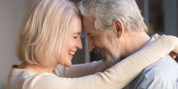Senior couple embracing and supporting each other, representing emotional connection and challenges of hearing loss.
