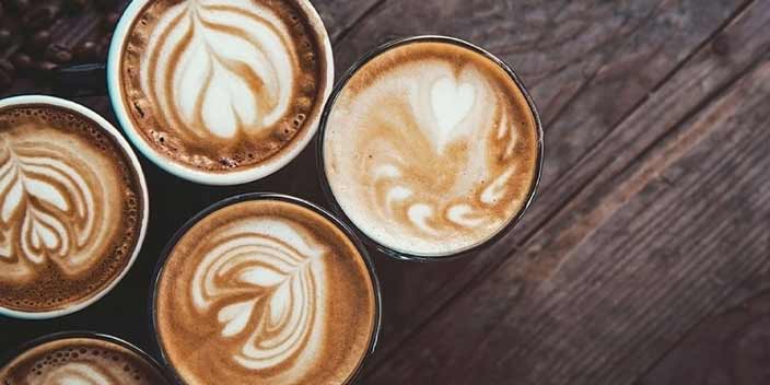 Lattes with heart-shaped latte art on a wooden table, related to coffee and tinnitus.