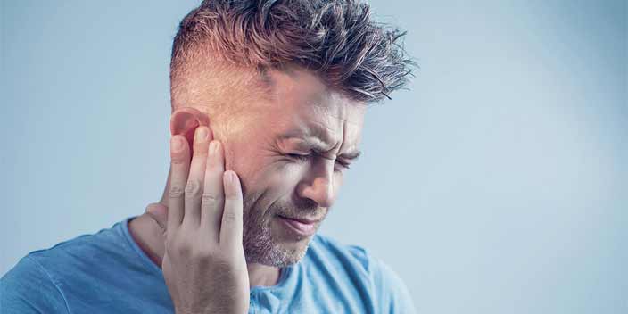 Man touching his ear, experiencing symptoms associated with tinnitus