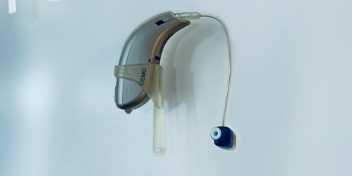 Behind-the-ear hearing aid with a blue earbud attachment.