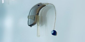 Behind-the-ear hearing aid with a blue earbud attachment.