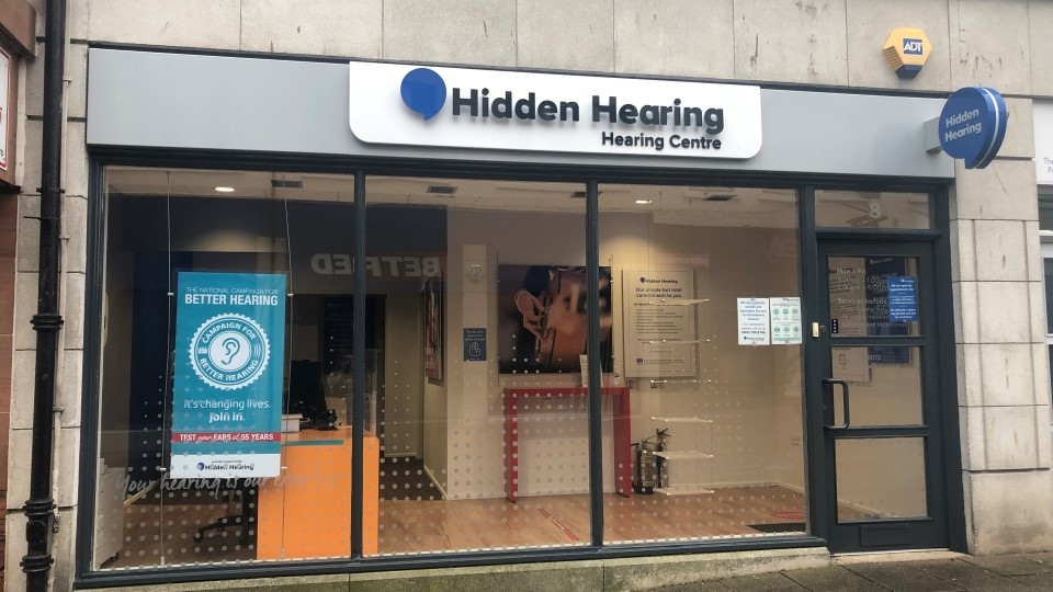 Hidden Hearing Dumfries clinic storefront with signage and glass windows showcasing interior details.