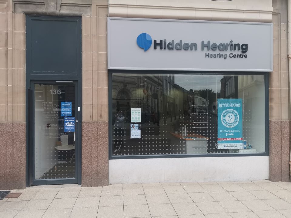 Exterior view of Hidden Hearing Falkirk clinic with a glass storefront and signage displaying the clinic name and opening hours.