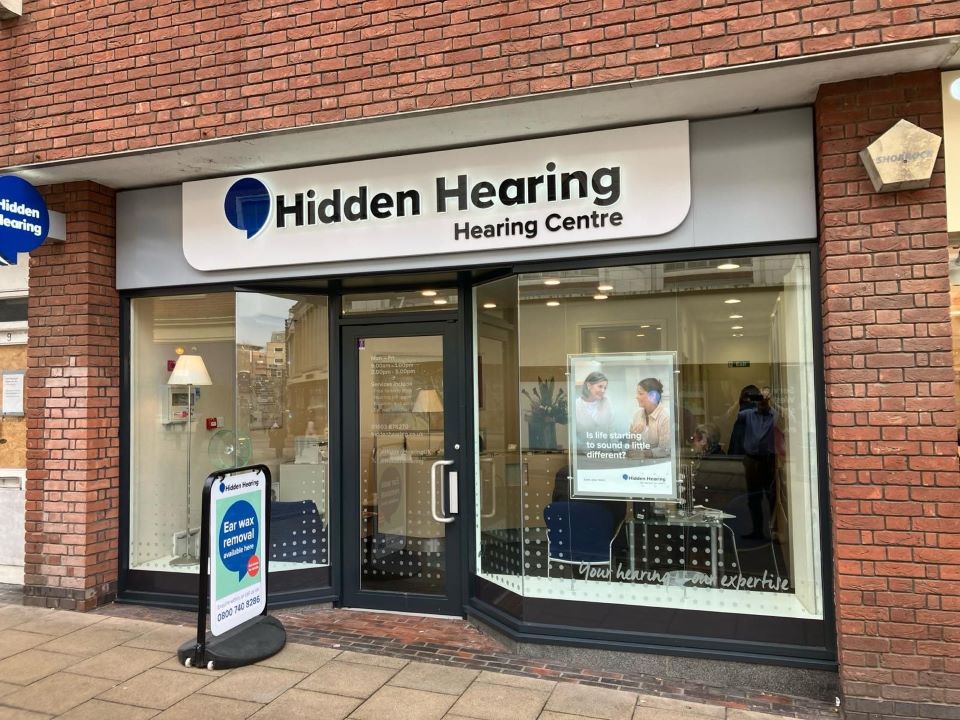Exterior view of Hidden Hearing Hearing Centre in Norwich with signage and promotional poster in the window.