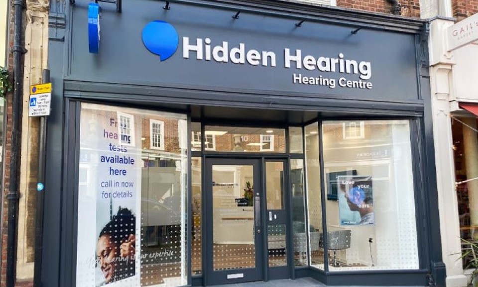 Hidden Hearing St Albans clinic exterior with signage and glass windows displaying promotional materials.