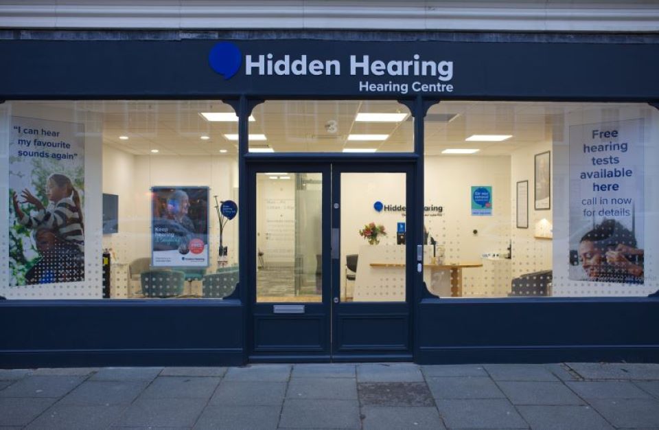 Hidden Hearing Chichester clinic storefront with signage promoting free hearing tests and customer testimonials.