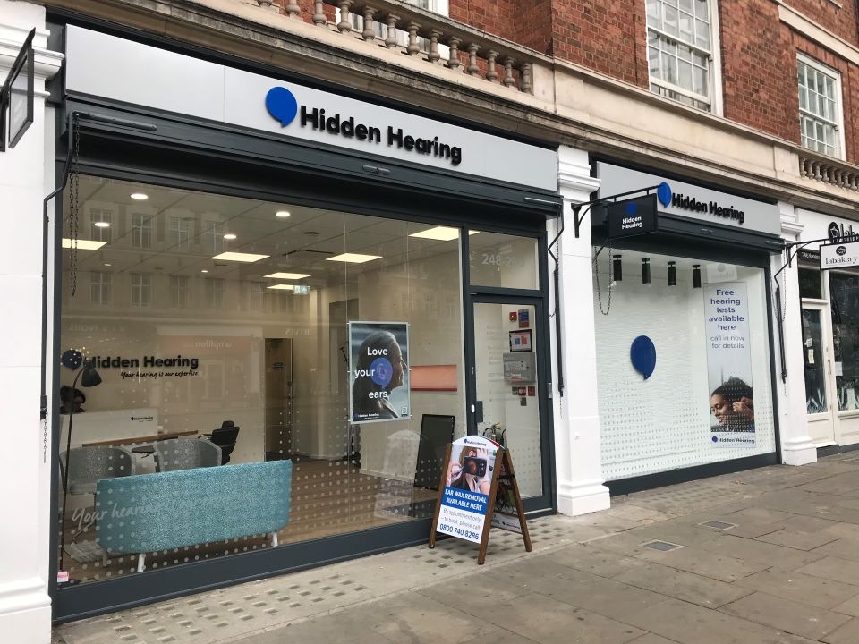 Hidden Hearing Ipswich clinic front with signage, large glass windows, and posters advertising hearing care services.