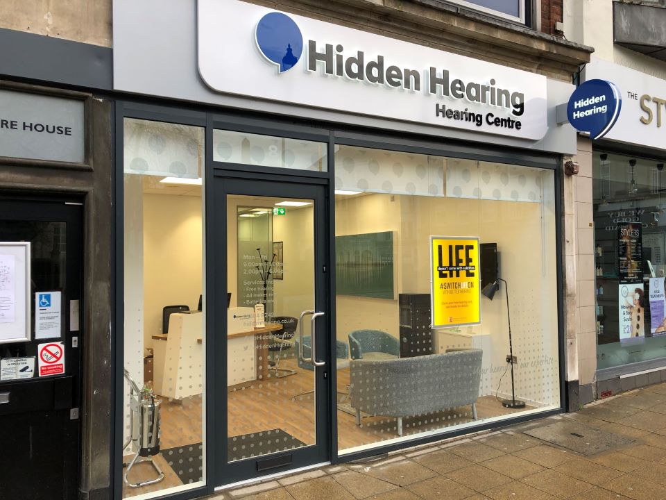 Hidden Hearing Northampton clinic storefront with glass entrance, branded signage, and view of the reception area.