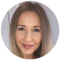 A person with long, straight, light-brown hair is centered in the frame. The background shows a neutral, indoor setting with pale-colored walls.