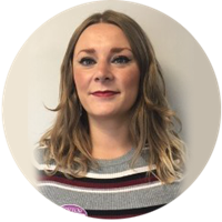 A person wearing a striped sweater with shoulder-length wavy hair stands against a neutral background.
