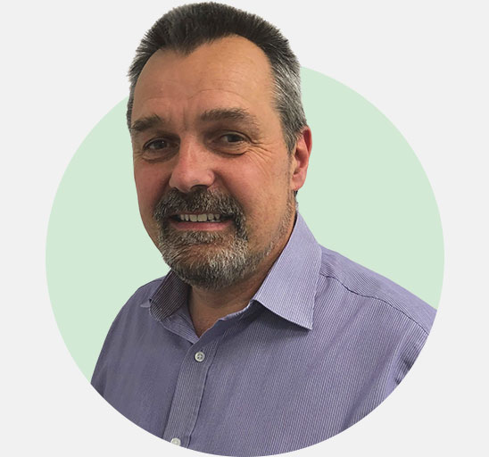 David Shepherd, hearing care specialist in a striped purple shirt with a light green background.