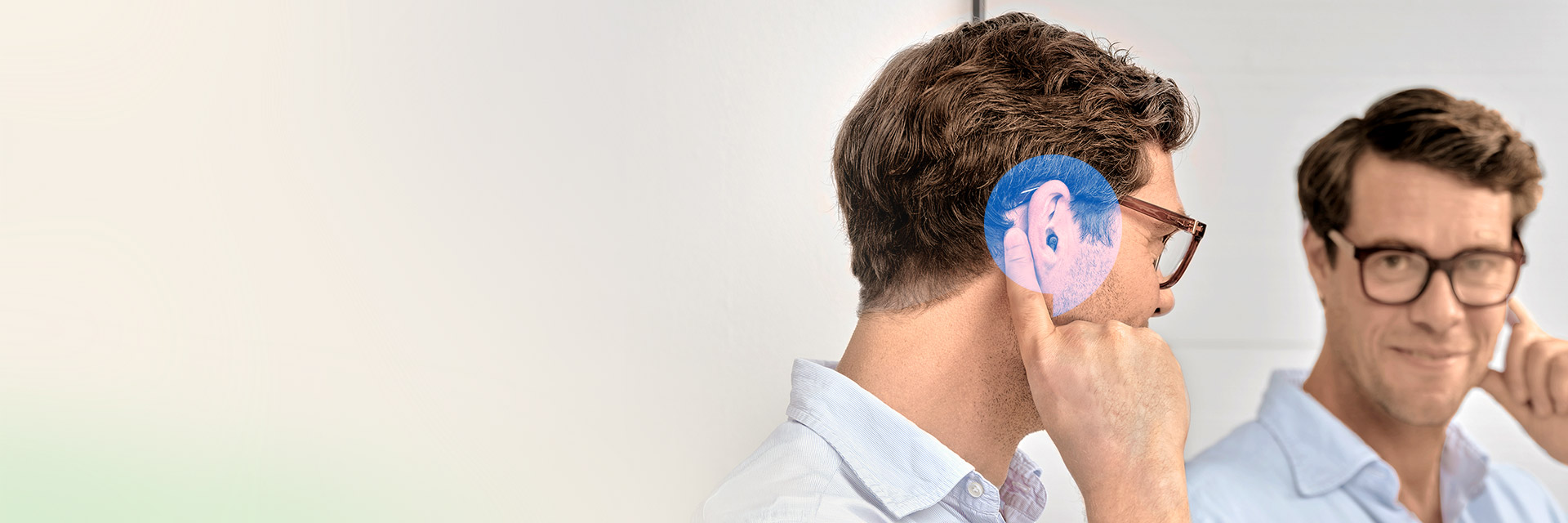 Oticon Zeal hearing aid worn by a man looking in the mirror. - Audika